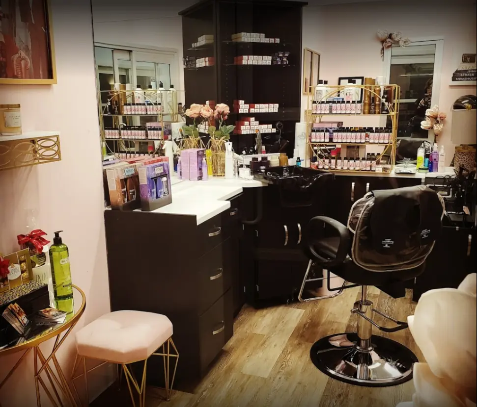Interior of a beauty salon featuring a styling station, products on shelves, and a pink stool